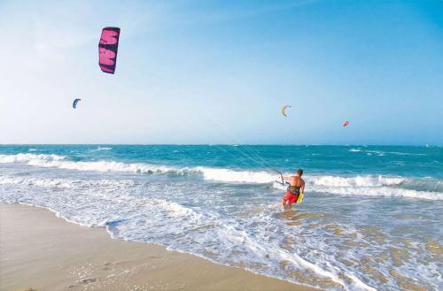 a man standing in the ocean flying a kite at Viva Tangerine by Wyndham, A Trademark All Inclusive in Cabarete