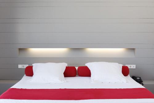 1 cama con almohadas rojas y blancas en una habitación en Hotel Spa Calagrande Cabo de Gata, en Las Negras