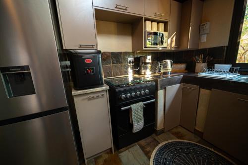 a small kitchen with a stove and a refrigerator at Bushveld Jewel - Close to Kruger in Hoedspruit