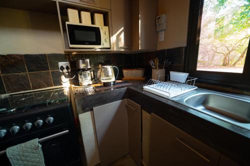 a kitchen with a sink and a microwave at Bushveld Jewel - Close to Kruger in Hoedspruit