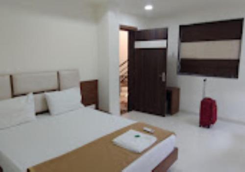 um quarto com uma cama e uma mala vermelha em Hotel Lotus Chandrapur em Chandrapur