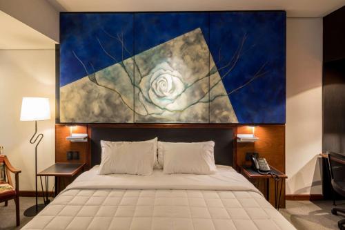 1 dormitorio con una gran pintura encima de una cama en Hilton Garden Inn Asuncion Aviadores Del Chaco en Asunción