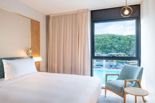 um quarto de hotel com uma cama e uma cadeira e uma janela em Radisson Hotel Saint Denis, La Reunion em Saint-Denis