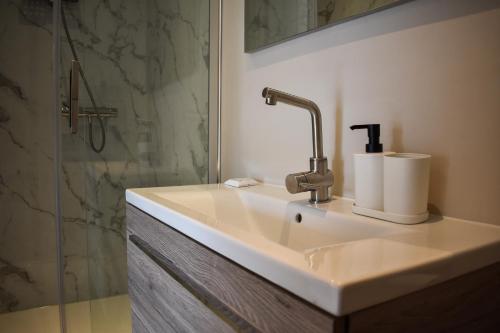 a white sink in a bathroom with a shower at Stijlvol appartement 'Moto' in centrum Franeker. in Franeker