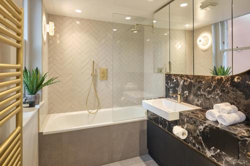 W łazience znajduje się wanna, umywalka i prysznic. w obiekcie Darley House by Viridian Apartments w Londynie