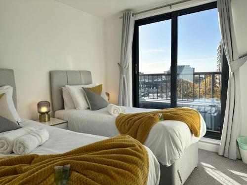 a bedroom with two beds and a large window at BEST PRICE! - HUGE 3 Bed 2 Bath City Centre Newly Refurbished Apartment, Up to 7 guests - FREE SECURE PARKING - SMART TV - SINGLES OR KING SIZE BEDS in Southampton