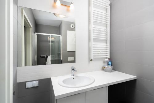 a white bathroom with a sink and a mirror at Jesionowa Standard Apartment in Wrocław