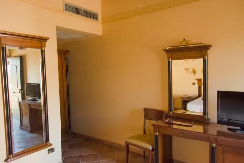 a hotel room with a desk and a mirror at Hotel Quadrifoglio Roma Eur in Mostacciano 