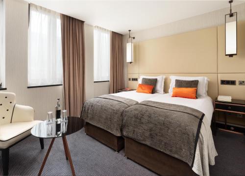 a hotel room with a large bed and a chair at Montcalm Royal London House, London City in London