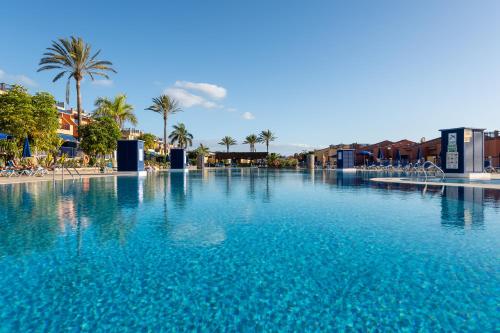 a large swimming pool with blue water and palm trees at Meloneras by the sea in San Bartolomé