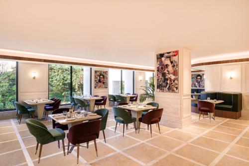 a restaurant with tables and chairs and windows at Aurika, Mumbai International Airport - Luxury by Lemon Tree Hotels in Mumbai