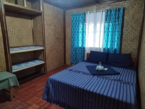 a bedroom with a blue bed and a window at Itaytay inn in San Vicente