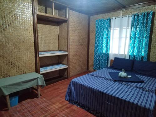 a bedroom with a blue bed and a window at Itaytay inn in San Vicente