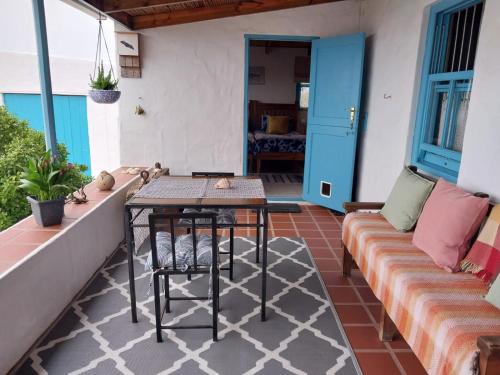 een patio met een tafel en een bank bij Foot-loose & Fancy Free in St Helena Bay