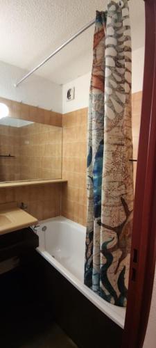 a bath tub with a shower curtain in a bathroom at Sympathique Appartement Le Chamois Blanc Chamonix, Parking in Chamonix
