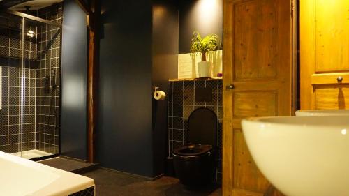 a bathroom with a black toilet and a sink at Ferme Fleurie in Bergesserin