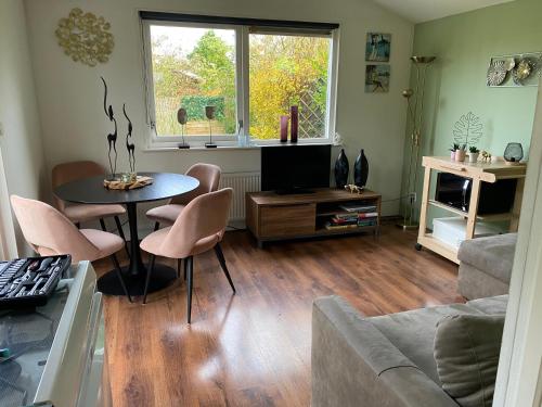 een woonkamer met een tafel en stoelen en een bank bij Tiny house Schoorl Bergen NH in Warmenhuizen