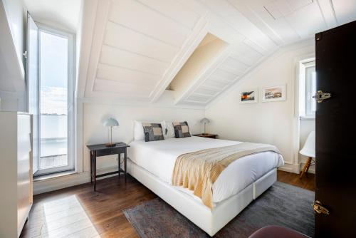 a white bedroom with a bed and a window at Chiado Trindade Apartments | Lisbon Best Apartments in Lisbon