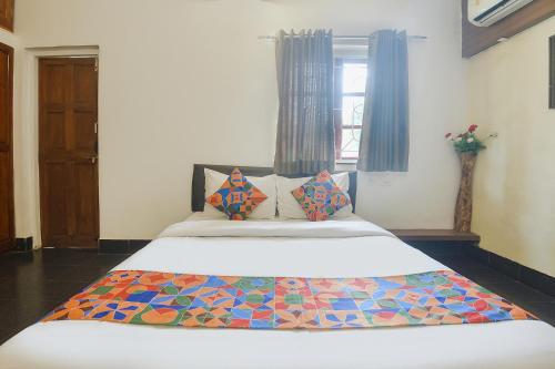 FabExpress Royal Baga Residency في أولد غوا: غرفة نوم مع سرير مع بطانية ملونة عليه