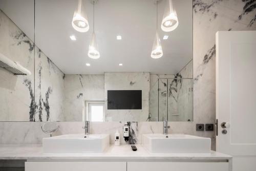 a bathroom with two sinks and a tv on the wall at Chiado Trindade Apartments | Lisbon Best Apartments in Lisbon