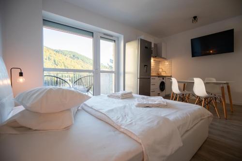 a bedroom with a white bed and a large window at Large Studio - Balcony - Spa and Gym in Building - Free Parking in Sinaia