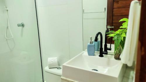 ein weißes Bad mit einem Waschbecken und einer Dusche in der Unterkunft Apartamento Casal beira mar, Ventos de Sibaúma in Tibau do Sul