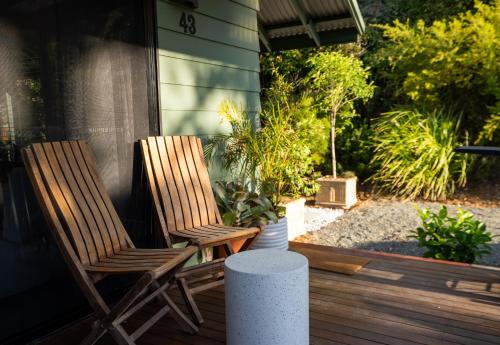 2 chaises en bois assises sur une terrasse couverte ornée de plantes dans l'établissement Mike's Kangaroo Valley, à Kangaroo Valley