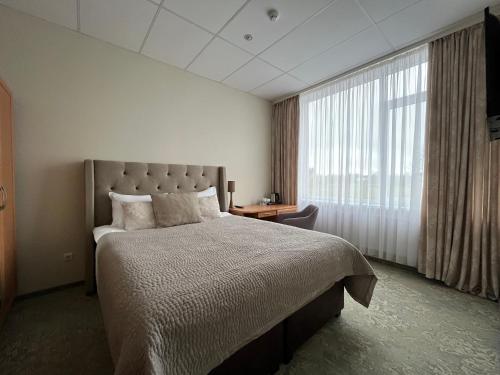 una camera con un grande letto e una grande finestra di Hotel - cafe Naujoji Akmenė a Naujoji Akmenė