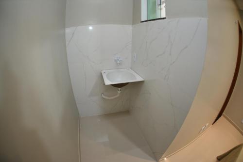 a white bathroom with a sink and a mirror at Residencial Rosê - flats mobiliados in Ubajara