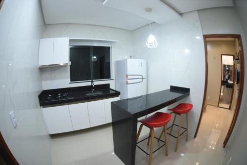 a kitchen with a black counter and two red stools at Residencial Rosê - flats mobiliados in Ubajara