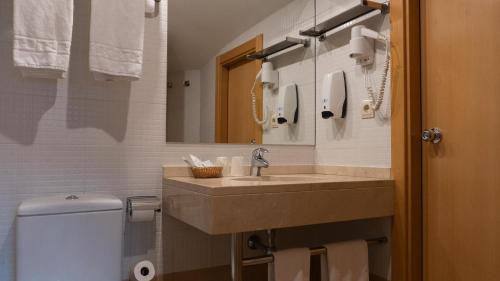 a bathroom with a sink and a toilet and a mirror at Annapurna M&P in Ordino