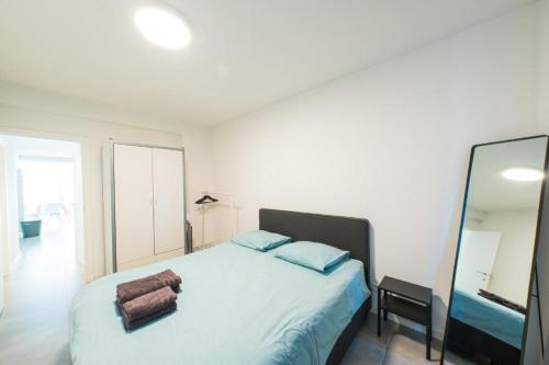 a bedroom with a bed with blue pillows and a mirror at Luxury apartment with free parking in Ostend
