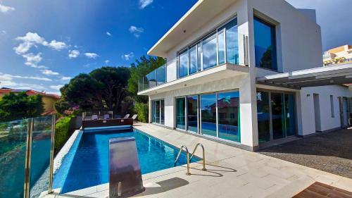 a large house with a swimming pool in front of it at Villa Madeira by LovelyStay in Caniço