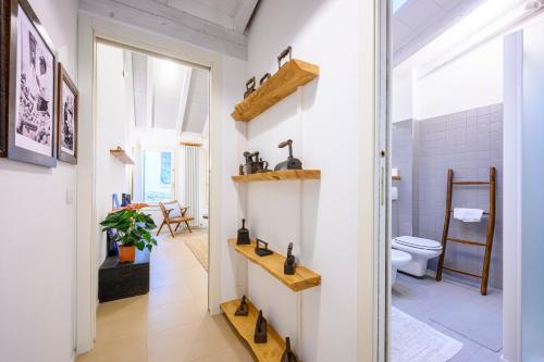 La salle de bains est pourvue de toilettes et d'étagères en bois. dans l'établissement Skylight Duplex in Historic Center, à Parme