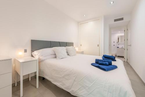 a bedroom with a large white bed with blue pillows on it at Js Villas rental Ap La Perla 5 Puerto Pollensa in Port de Pollensa