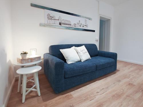 a blue couch in a living room with a stool at Casa Carlotta al Portello, vicino al centro e all'ospedale in Padova