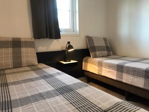 een slaapkamer met 2 bedden en een lamp op een nachtkastje bij Vakantiehuis voor 4 personen in Opheusden