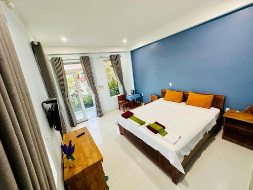 sypialnia z dużym łóżkiem i niebieską ścianą w obiekcie Co Bon Beachside w Hoi An