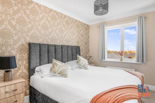 ein Schlafzimmer mit einem großen Bett und einem Fenster in der Unterkunft OnSiteStays - Cosy 2-Bedroom Apartment with Free Parking, Wi-Fi & London Links in Northfleet