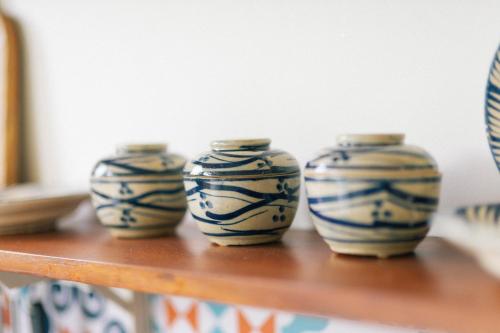 three blue and white vases sitting on a wooden shelf at Phòng Sầu Riêng(Durian Room) - Nhà Mơ Homestay in Ben Tre
