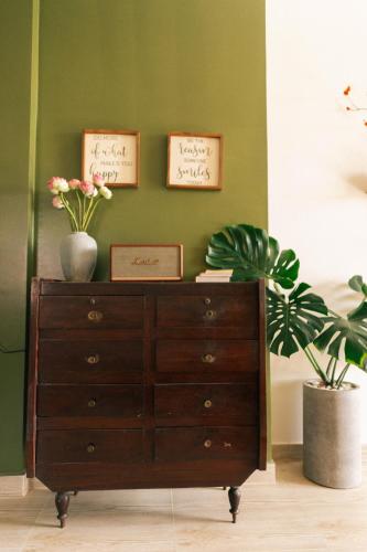 a wooden dresser with two pictures on a green wall at Phòng Sầu Riêng(Durian Room) - Nhà Mơ Homestay in Ben Tre