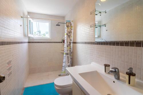 ein Badezimmer mit einem WC, einem Waschbecken und einem Spiegel in der Unterkunft Cozy 3-Bedroom Apartment with Pool Access near Bavaro Beach in Punta Cana