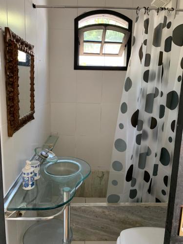 a bathroom with a glass sink and a shower curtain at Hostel Suite Home in Saquarema