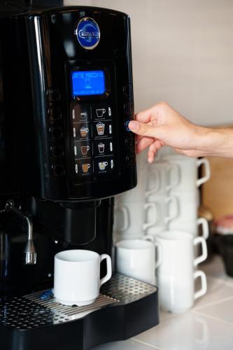 Une personne met des tasses à café au micro-ondes dans l'établissement Hotel ARCHE Fabryka Samolotów w Mielnie, à Mielno