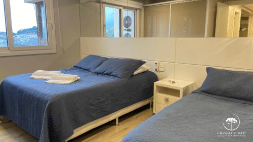 1 dormitorio con 2 camas y espejo en Apartamento Novo Centro de Gramado, en Gramado