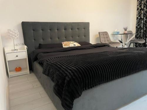uma cama com um cobertor preto e uma cadeira num quarto em Fancy Studio Arena Nationala em Bucareste