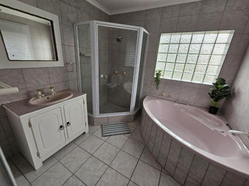 a bathroom with a tub and a sink and a shower at The Dutch Corner house in Langebaan