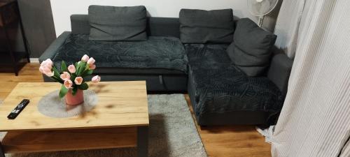 sala de estar con sofá y mesa con un jarrón de flores en Schöne sonnige Wohnung, en Jüchen