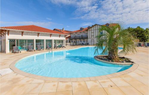 une grande piscine avec un palmier en face d'un bâtiment dans l'établissement 1 Bedroom Nice Apartment In Cassen, à Cassen