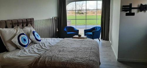 a bedroom with a bed and two blue chairs at Rêveries in Roeselare